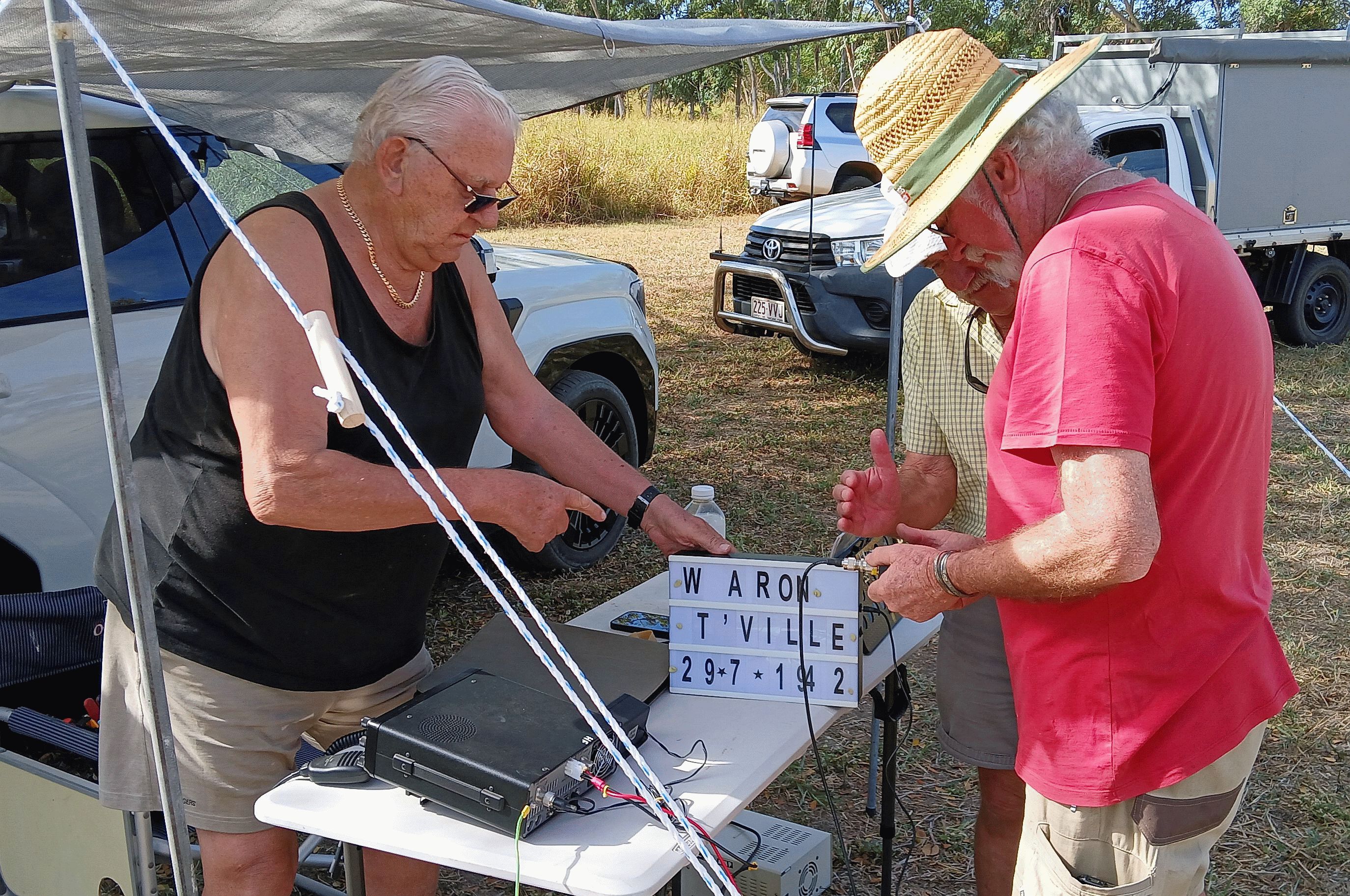 Members gathered around the WAR ON T'VILLE sign and HF rig