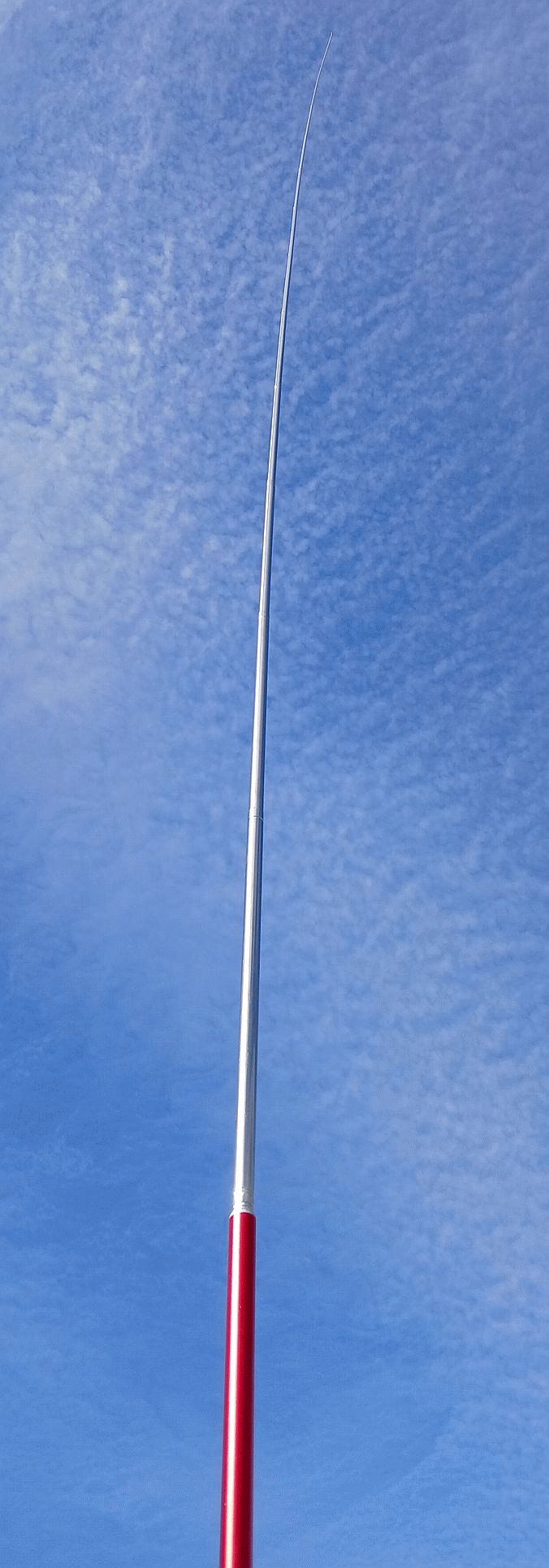 HF whip antenna against a cloudy sky