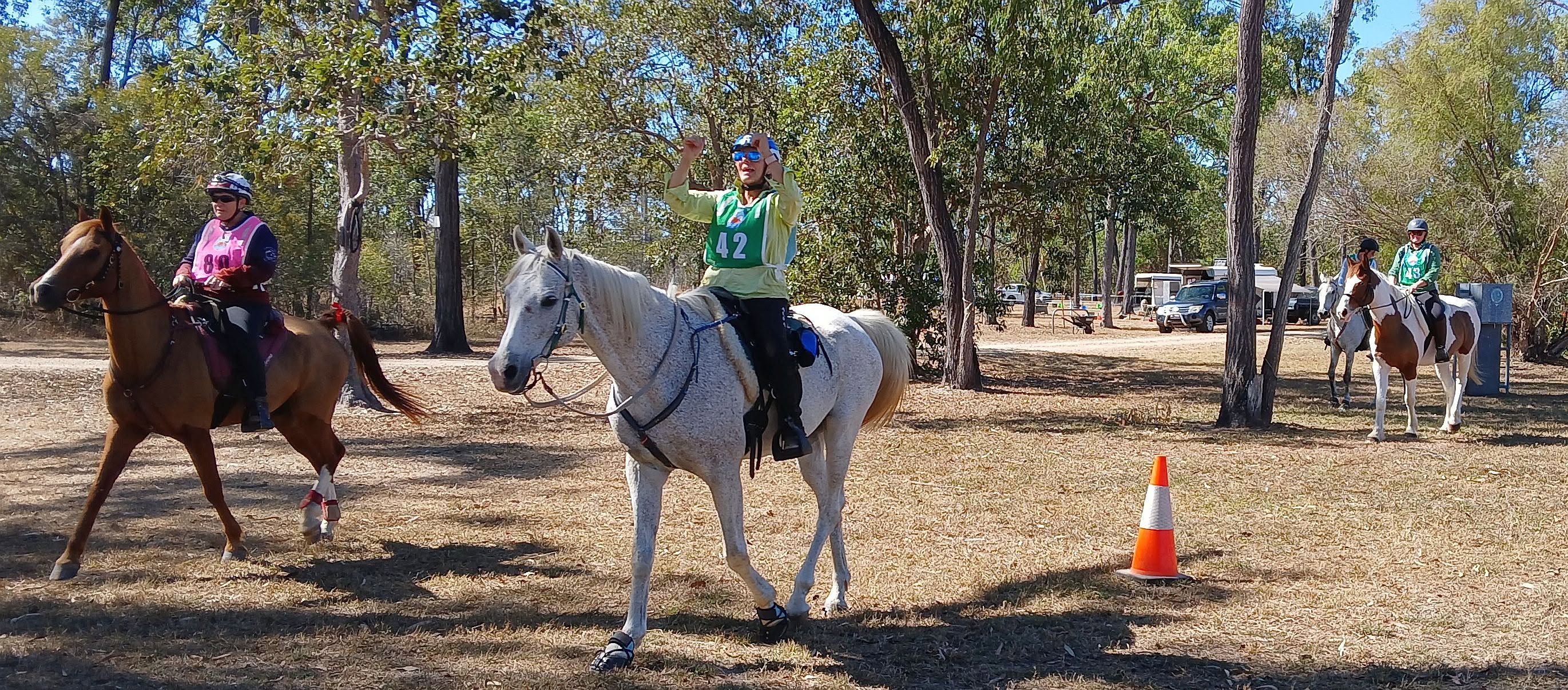 A group of endurance riders with support vehicles nearby