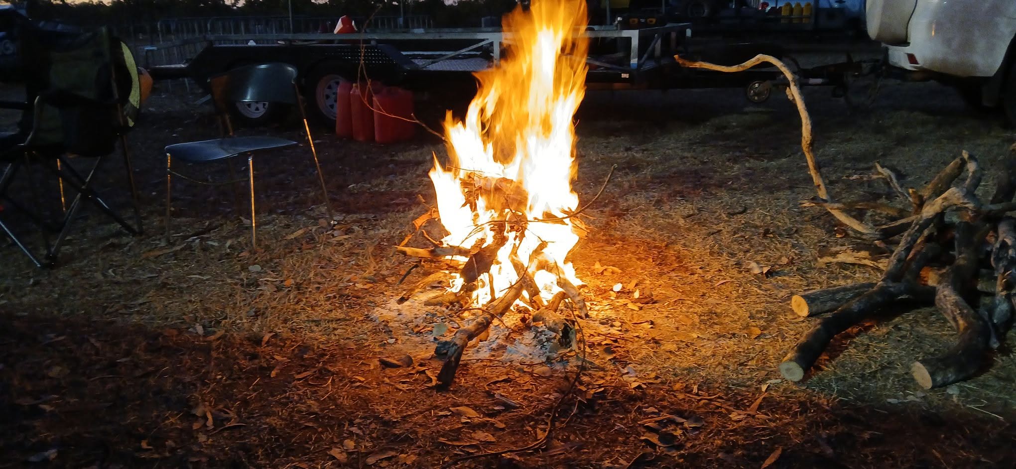 Campfire at night with trailers in the background