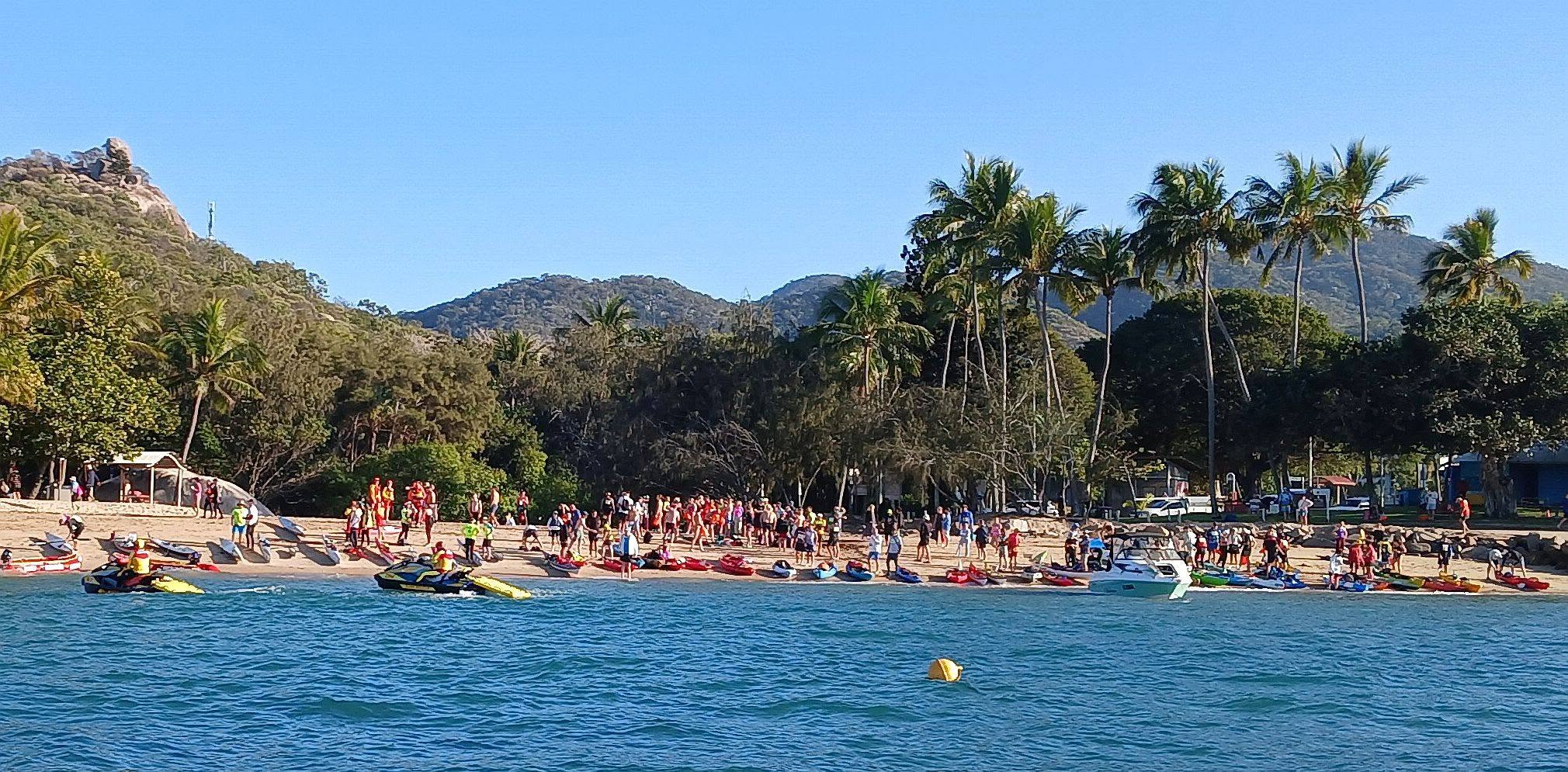 Swimmers and kayaks gathering on Picnic Bay beach ahead of the start