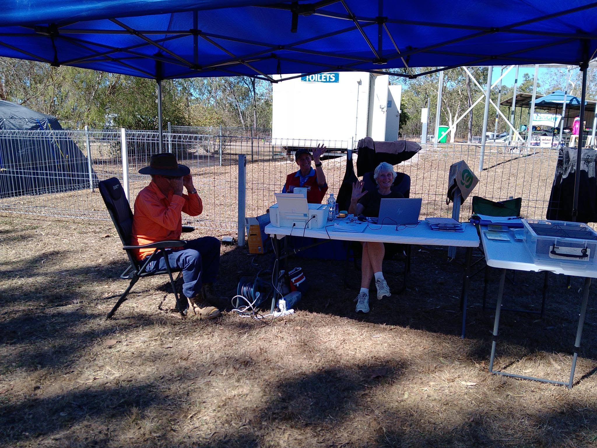 Ride Base volunteers waving from behind laptops under a blue gazebo