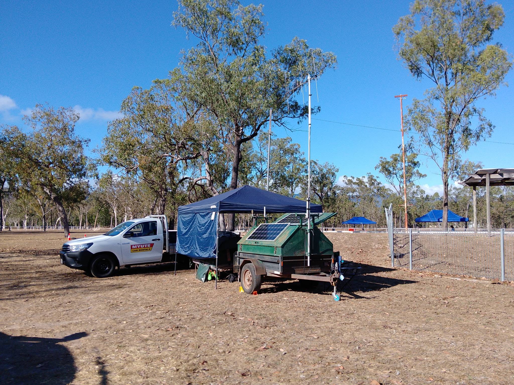 Radio trailer with solar panel and antenna mast beside a ute and gazebo