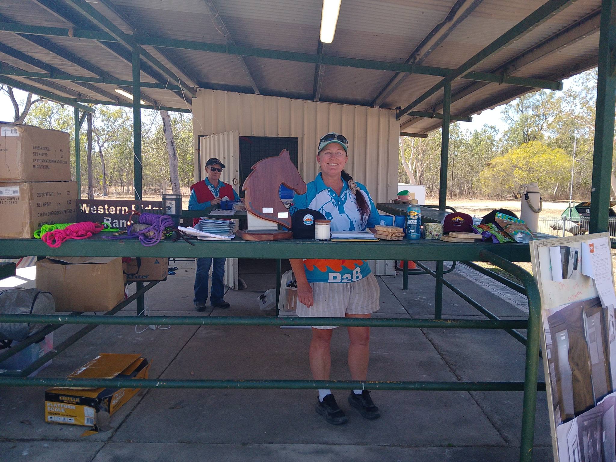B2B volunteer smiling at the presentation table with a horse-head trophy