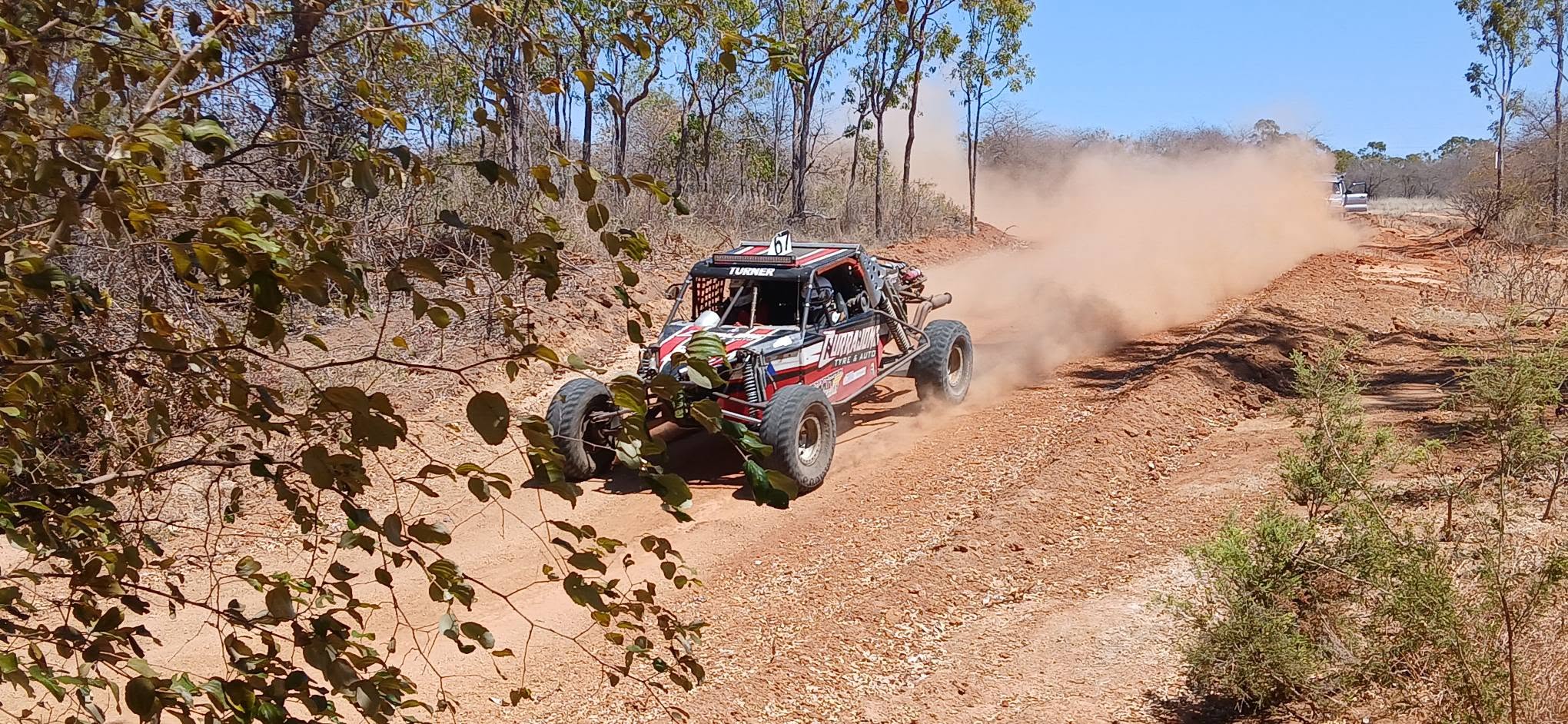 Race buggy powering through the bush trailing dust
