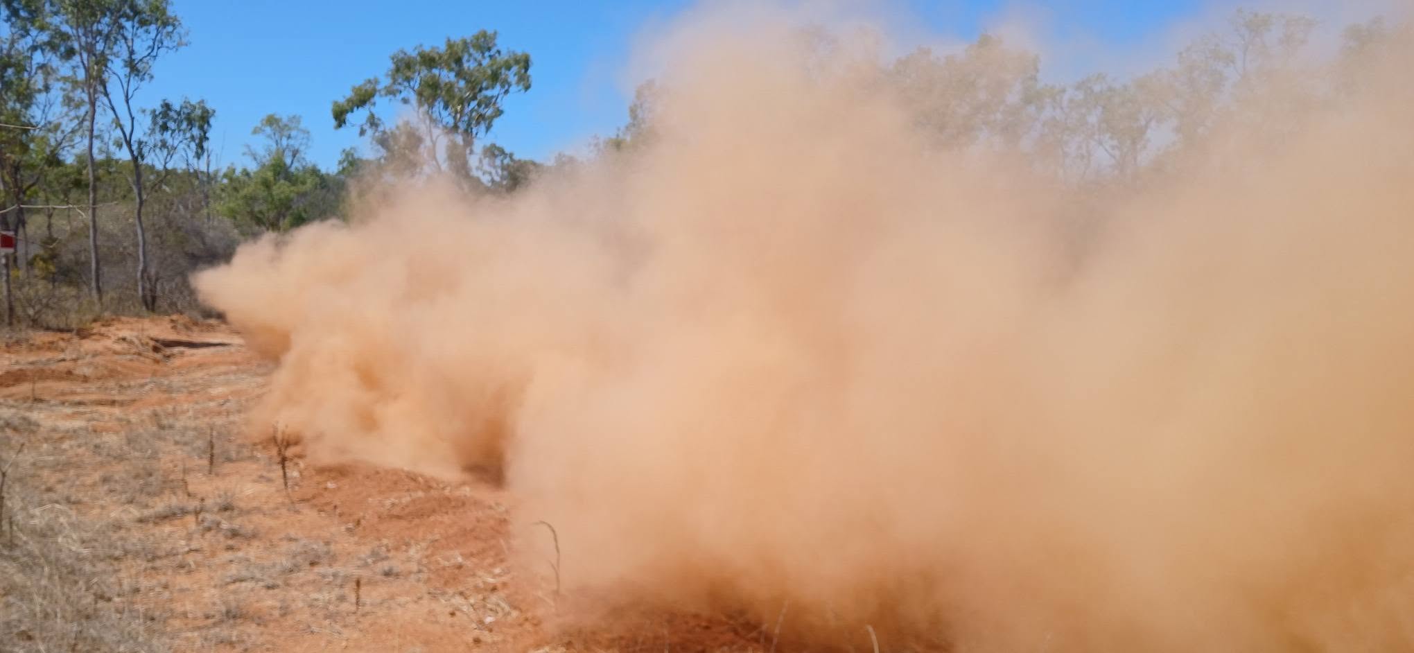 A cloud of dust hanging over the track after a buggy passes