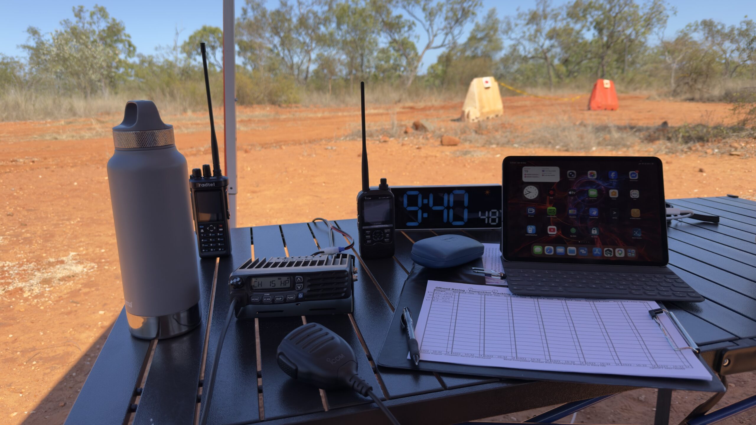 Checkpoint table with radios, microphone, logbook and tablet beside the track