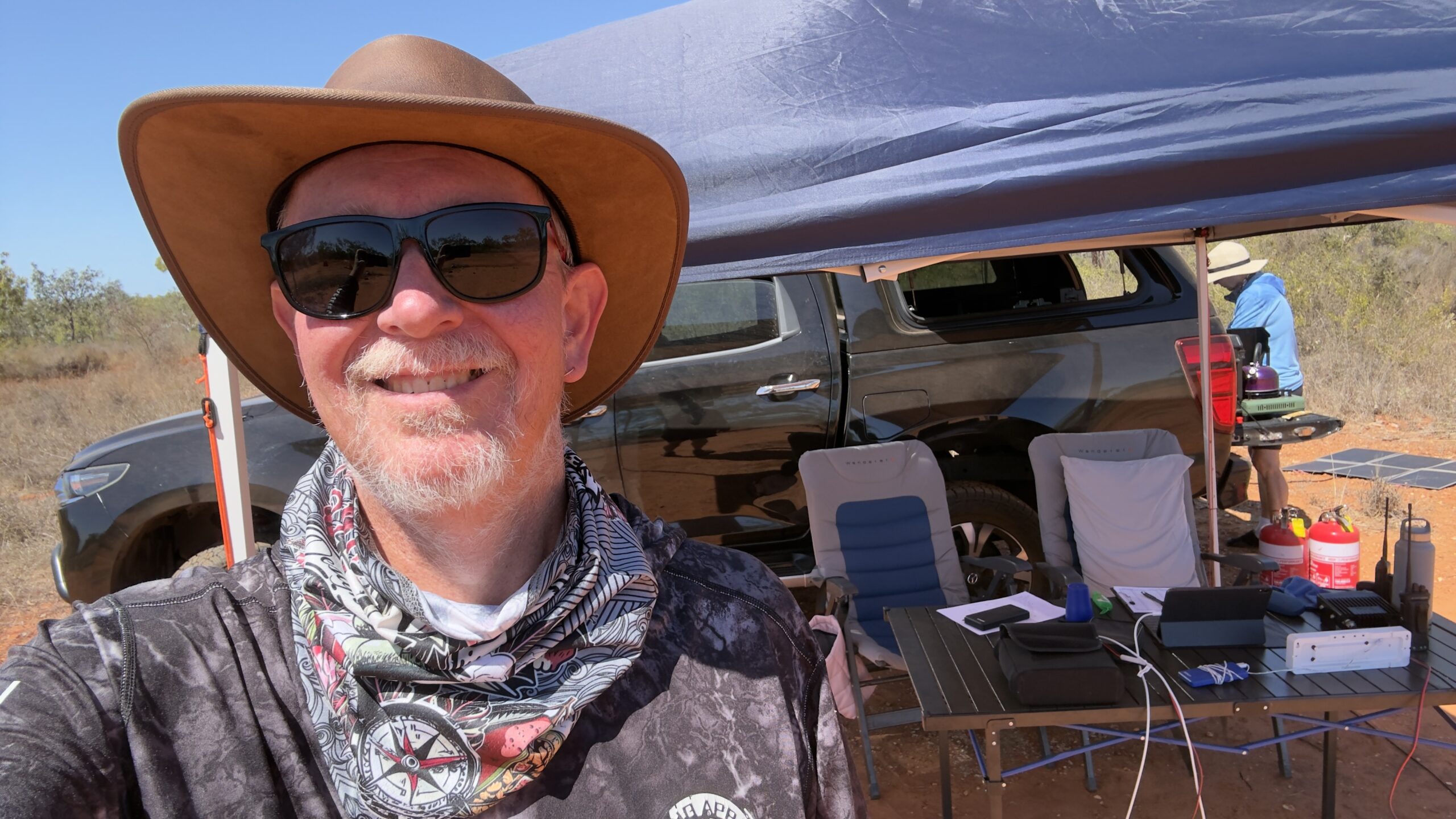 Volunteer selfie at a checkpoint camp under a gazebo